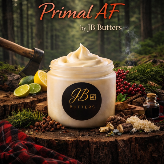 Jar of cream with 'JB Butters' logo on a wooden surface with nature elements, featuring 'Primal AF' branding.